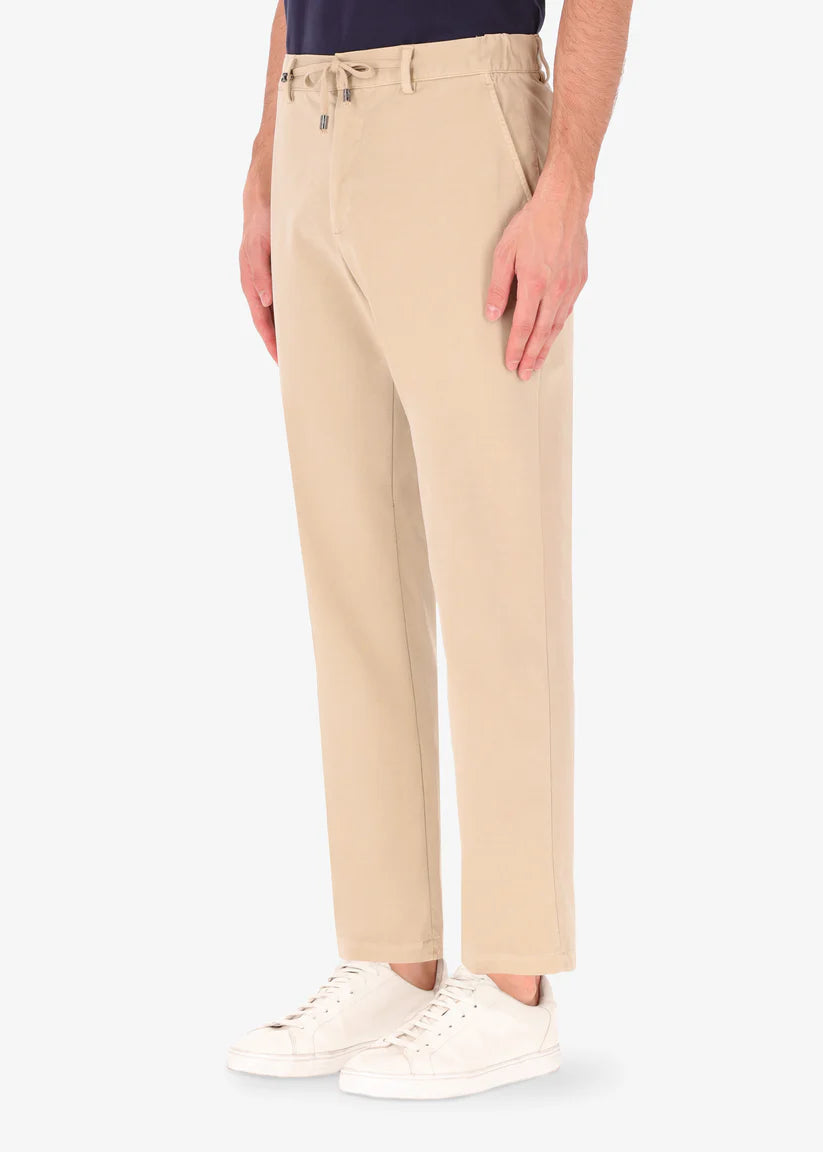 A side image of a model wearing reshaped chinos in tan from Distretto 12.