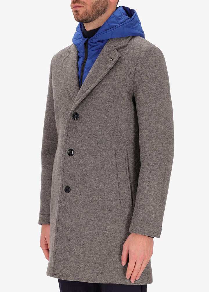 An image of a model wearing a Distretto12 coat Carlos in grey with light blue hood.