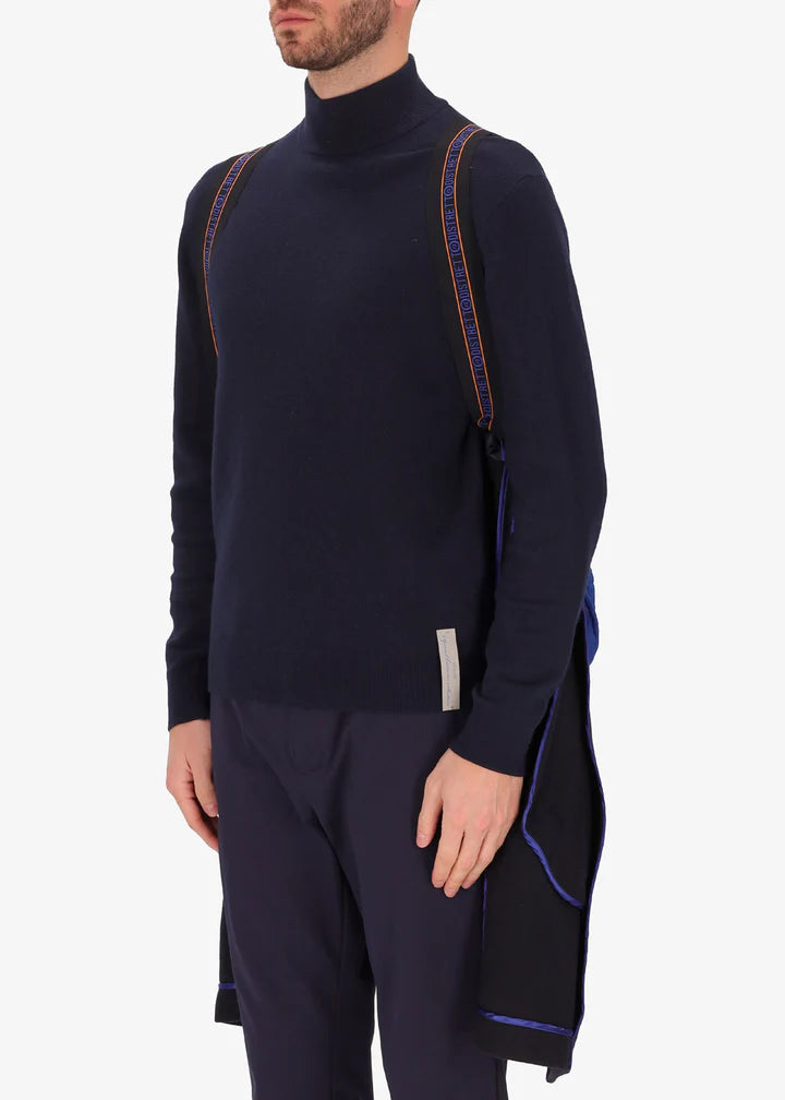 An image of a model wearing a Distretto12 coat Smith in blue with light blue hood by the suspenders.
