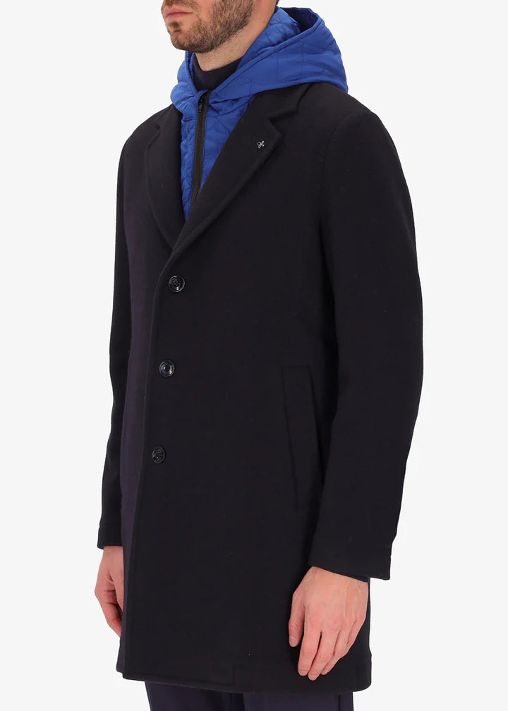 A side image of a model wearing a Distretto12 coat Smith in blue with light blue hood.