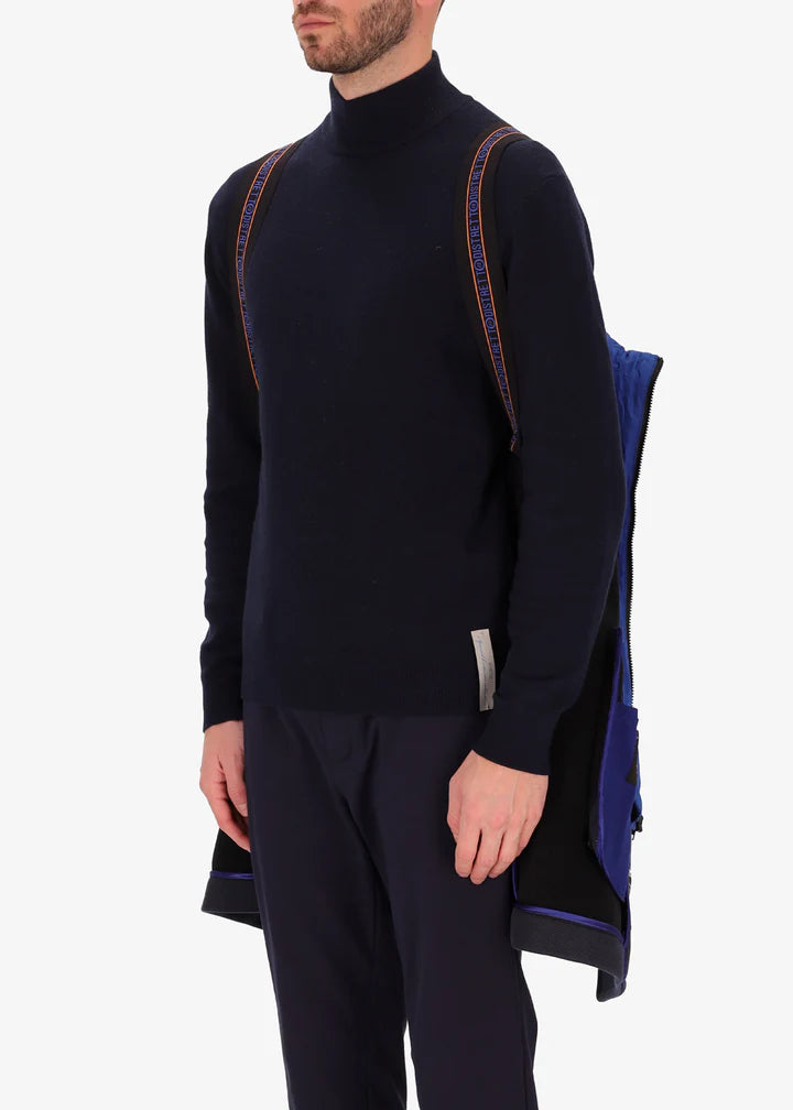 An image of a model wearing a Distretto12 peacoat cruise in blue with blue hood by the suspenders.