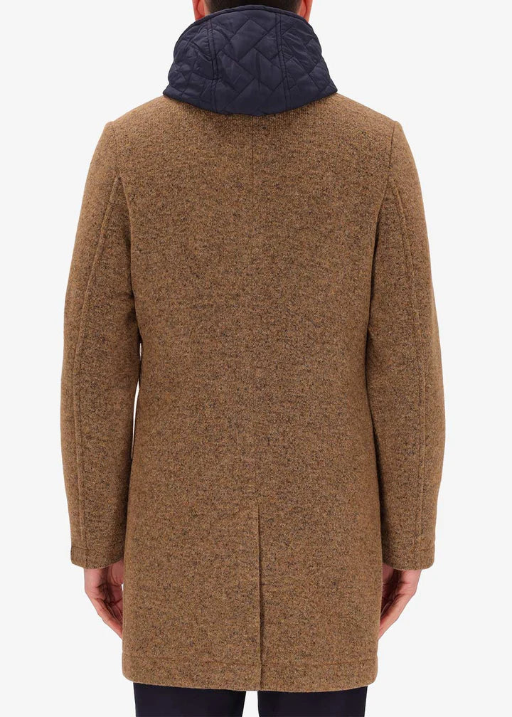 A back image of a model wearing Distretto12 coat Valentino in Tobacco, with a blue hood.