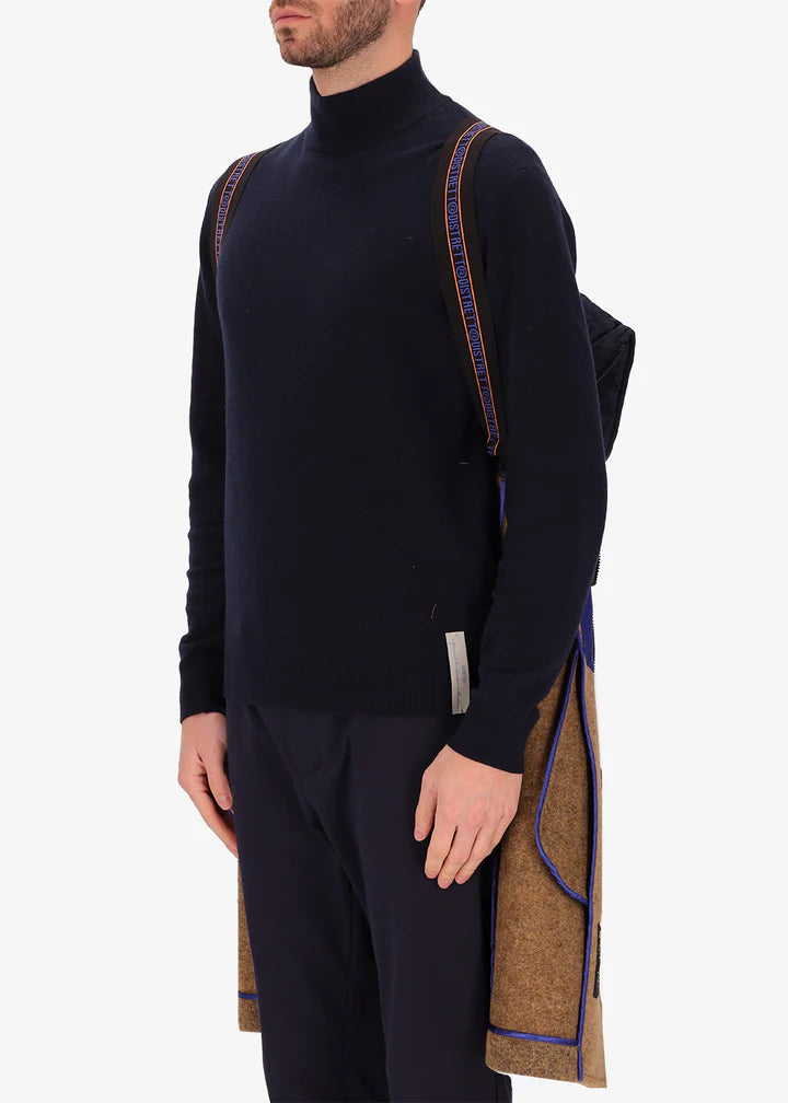 An image of a model wearing Distretto12 coat Valentino in Tobacco, with a blue hood by the suspenders.