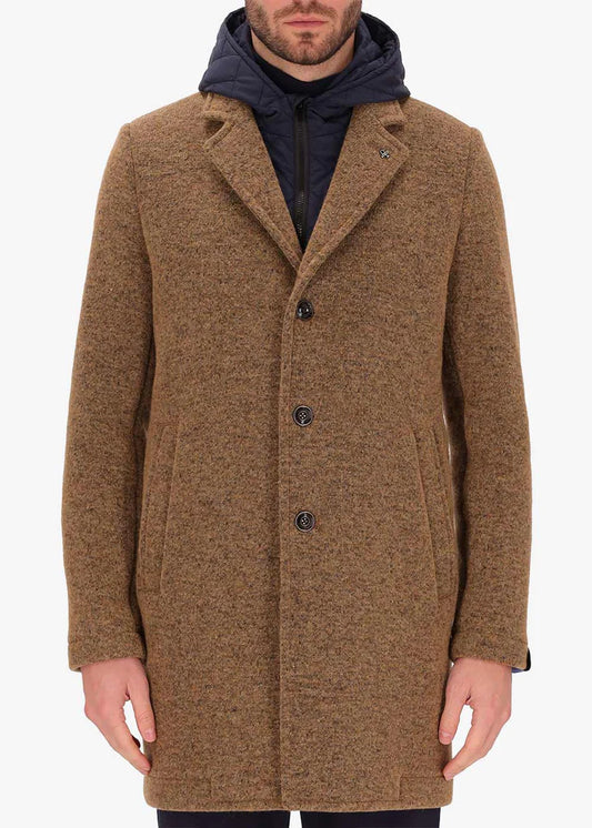 An image of a model wearing Distretto12 coat Valentino in Tobacco, with a blue hood.