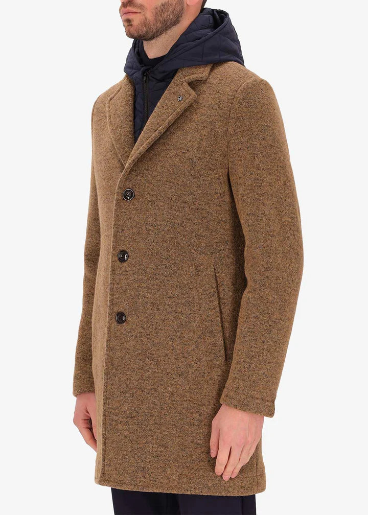 A side image of a model wearing Distretto12 coat Valentino in Tobacco, with a blue hood.