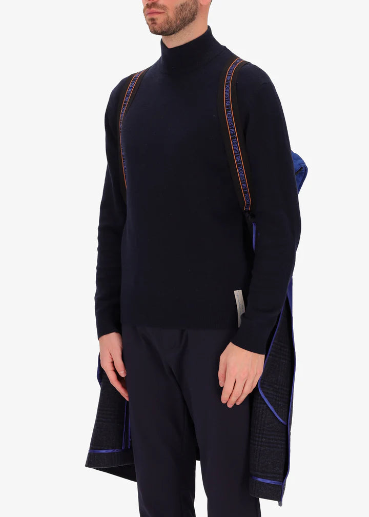 An image of a model wearing a Distretto12 coat Scaglia in blue with light blue hood by the suspenders.