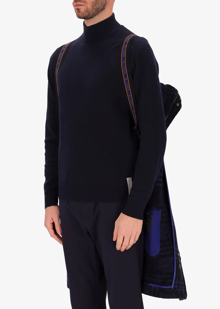 A front facing image of a model wearing Distretto tartan piquard coat in navy by the suspenders.