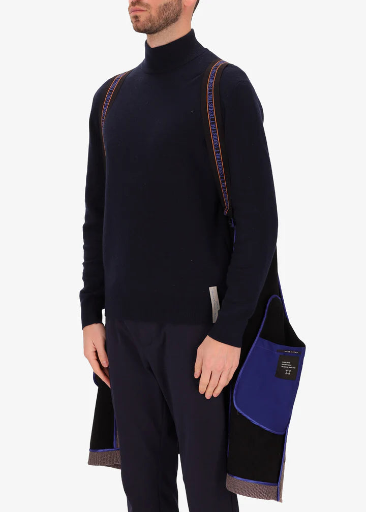 A front facing image of a model wearing a Distretto 12, trench coat in brown worn by suspenders.