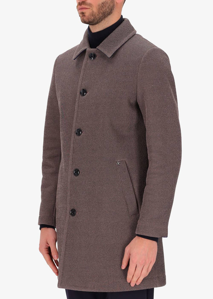 A side facing image of a model wearing a Distretto 12, trench coat in brown.
