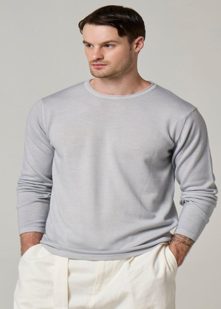 A picture of a model wearing a long sleeve, Wool&Co merino wool crewneck in grey.