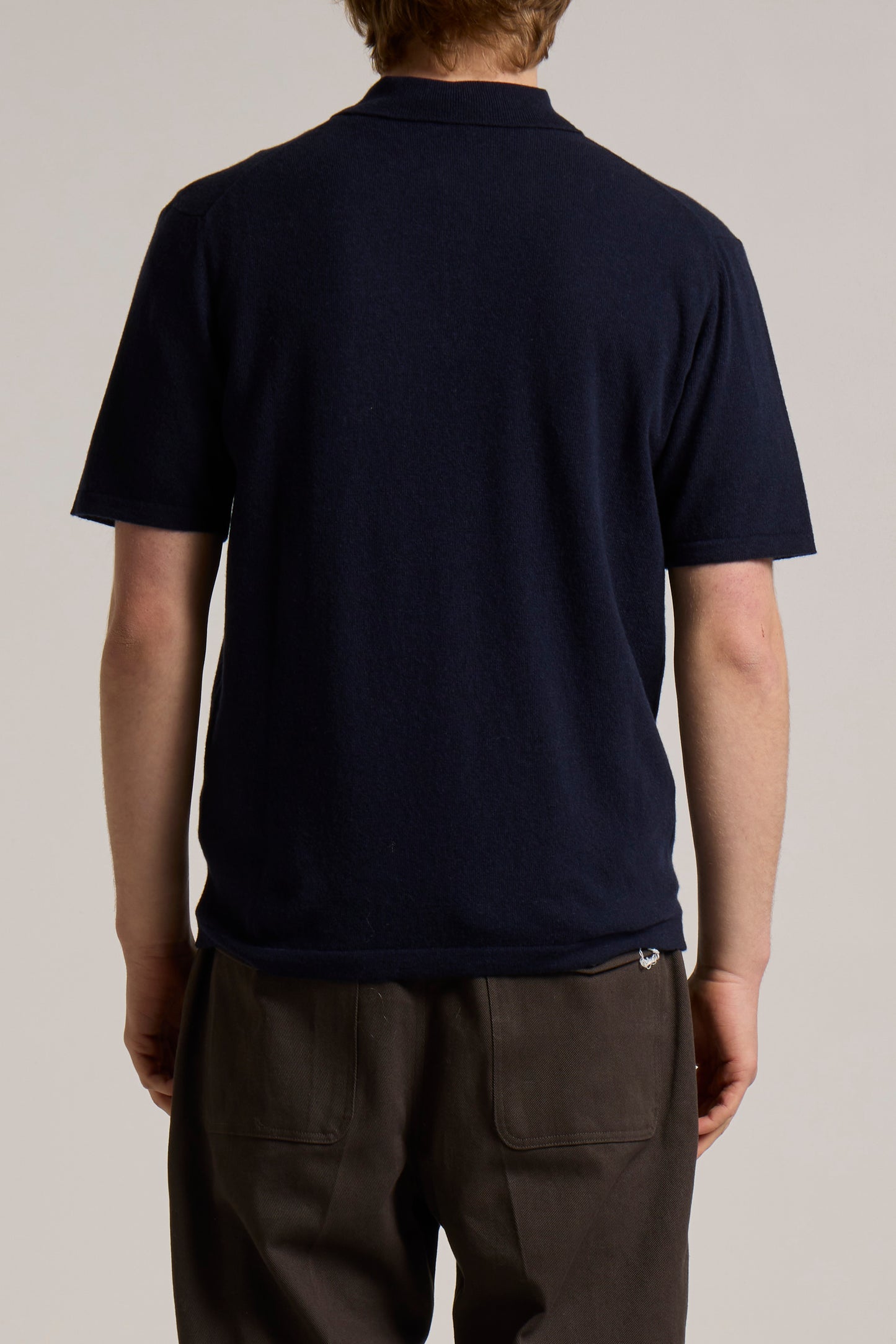 A model wearing a navy Wool&Co polo shirt knitwear.