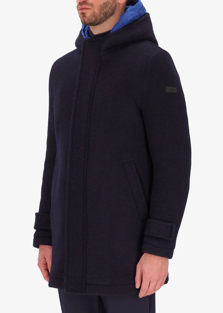 A side image of a model wearing a Distretto12 parka in blue with light blue hood.