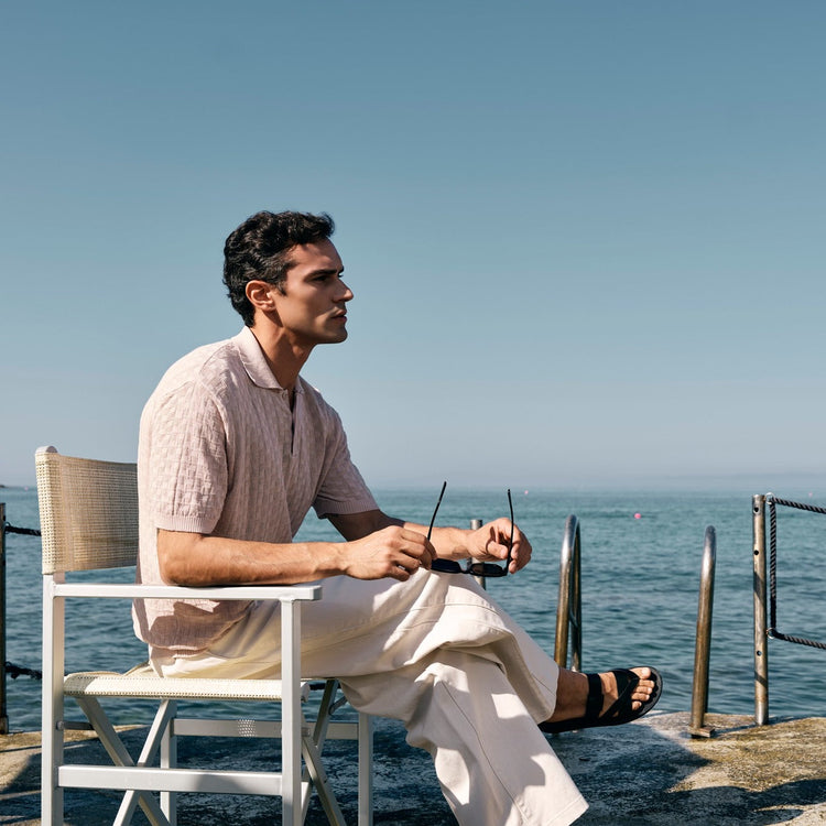 A man wearing a linen Wool&Co polo by the beach