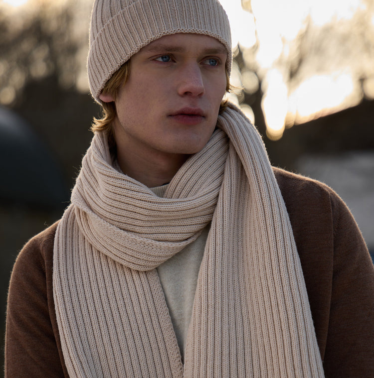 A picture of a man wearing a cream coloured knitted scarf