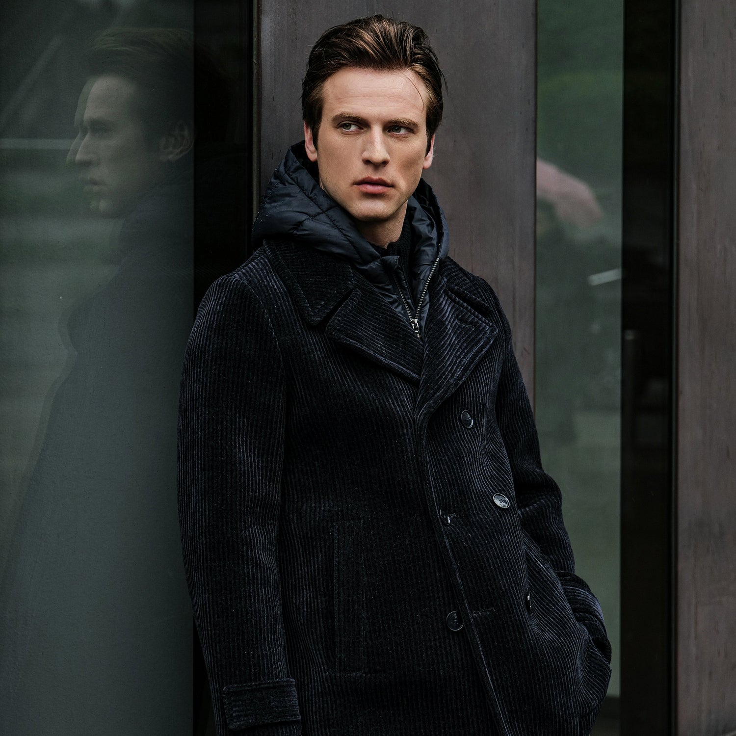 A man wearing a hooded cream overcoat with corduroy velvet detail