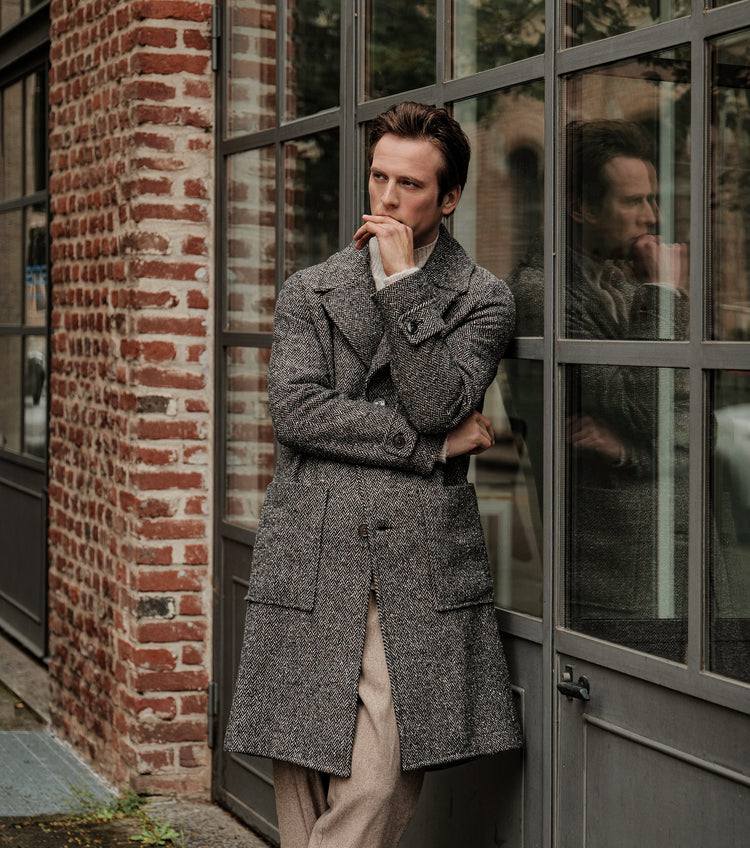 A man wearing a long wool overcoat in grey