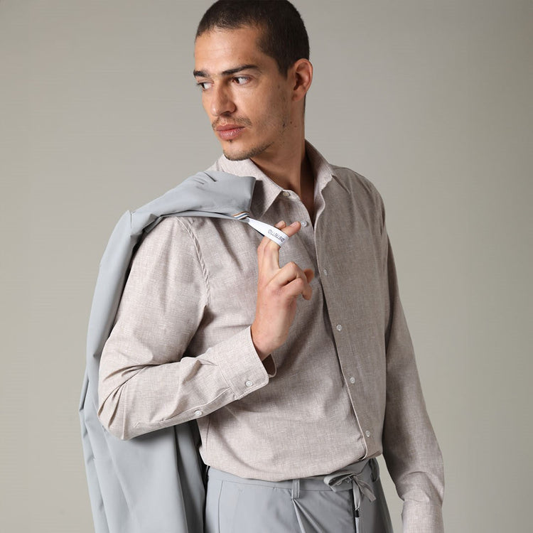 A model wearing a linen cotton blend shirt and a Distretto12 active suit, with the blazer slung over his shoulder.