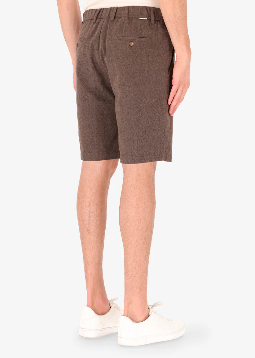 A back facing image of a model wearing linen shorts from Distretto 12.