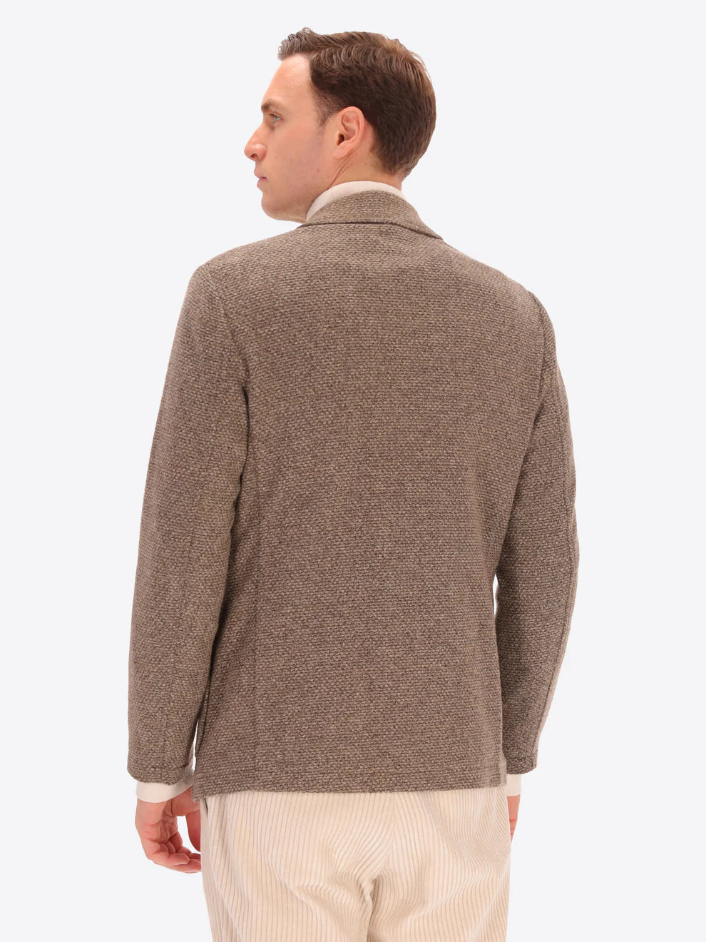 Male model wearing micro pattern jacket by distretto12 in camel colour with back view