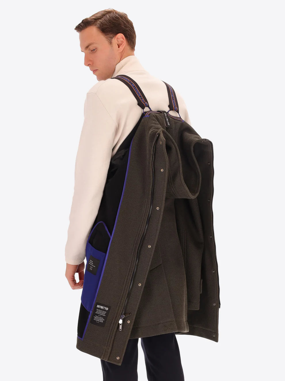 Male model wearing mud coloured parka by distretto12 with straps hung from back