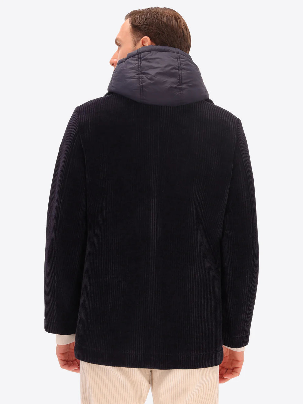 Male model wearing navy corduroy peacoat with detachable hood insert by distretto12 with back turned