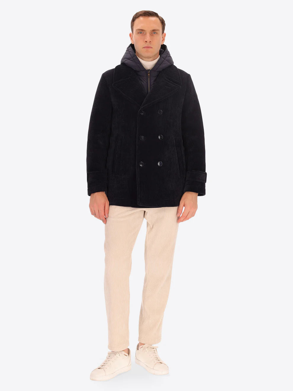 Male model wearing navy corduroy peacoat with detachable hood insert by distretto12 with cream corduroy trousers