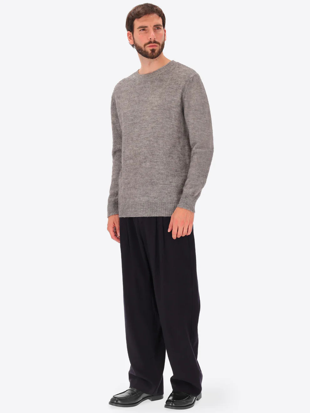 Male model wearing crew neck alpaca blend knitwear by distretto12 in grey with wide leg trousers