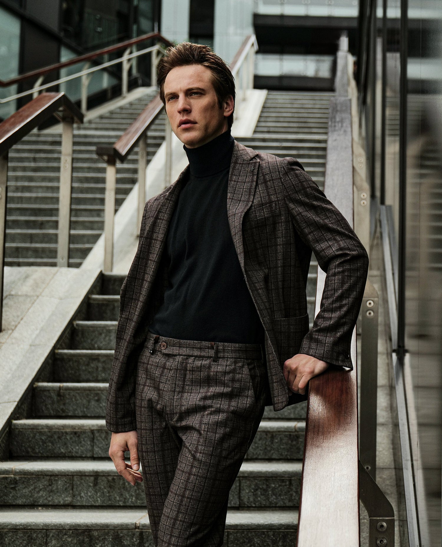 Man in a suit standing on stairs with a reflective surface behind him