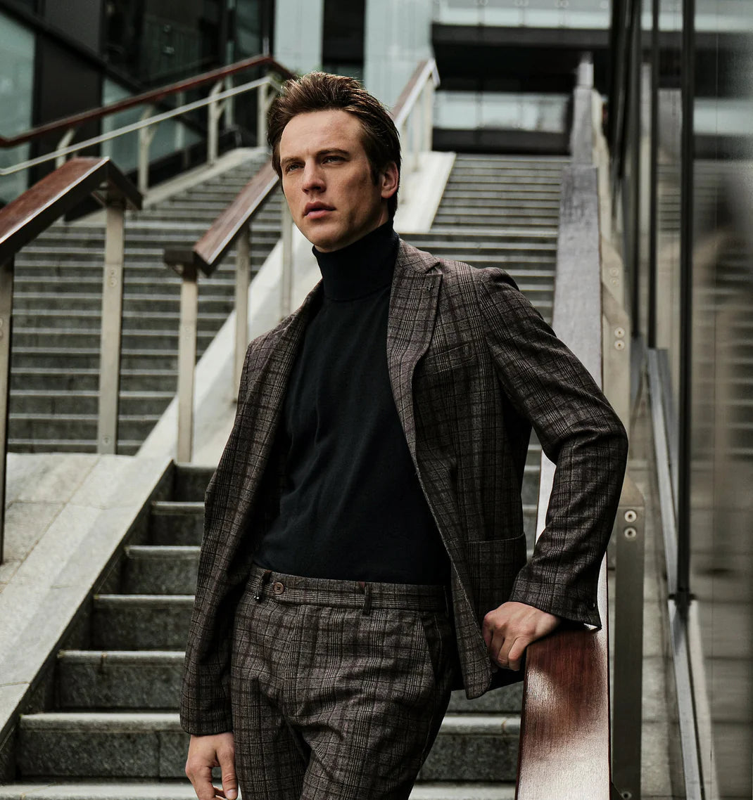 Man in a Distretto 12 checkered suit standing on a staircase with modern architecture in the background