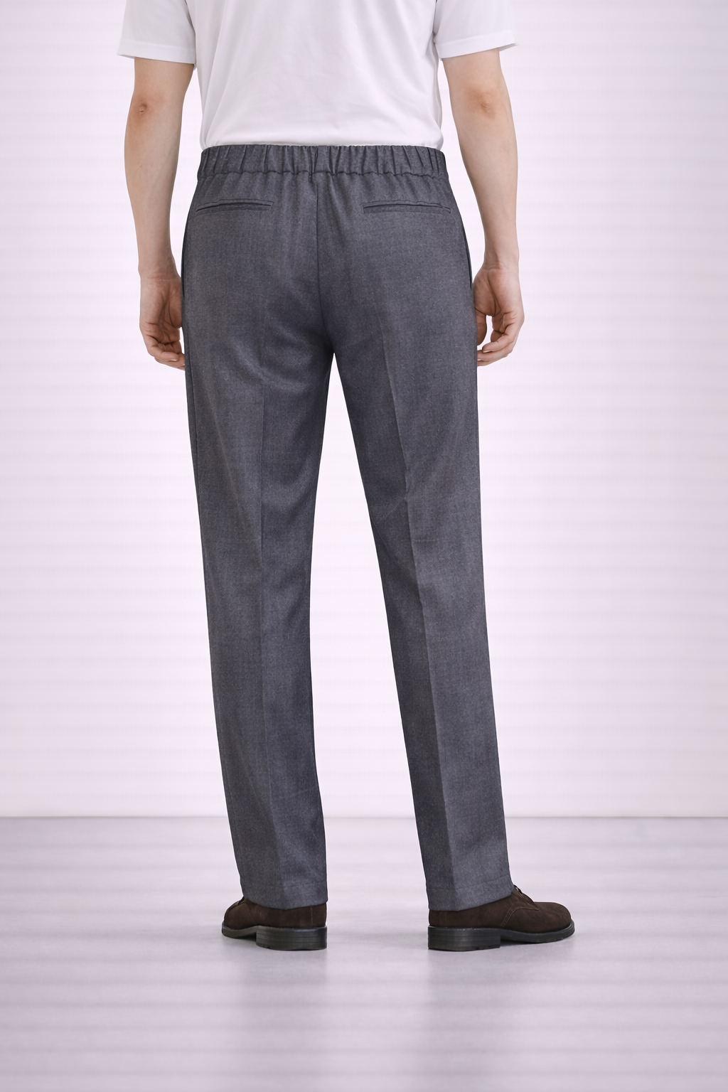 A back angled image of a model wearing Germano 1952 grey drawstring trousers with pleat.