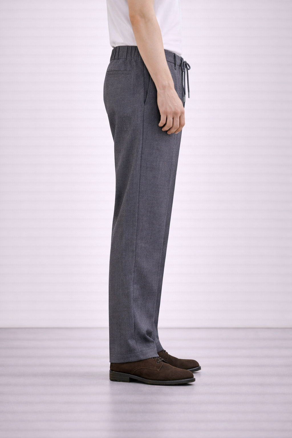 A side on image of a model wearing Germano 1952 grey drawstring trousers with pleat.