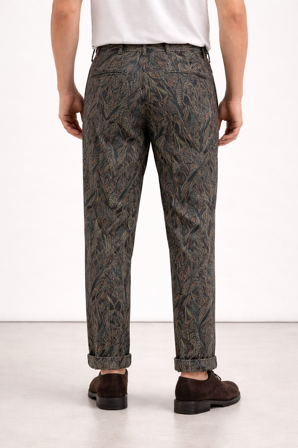 A model wearing Germano 1952 green corduroy trousers with forest themed pattern from behind.