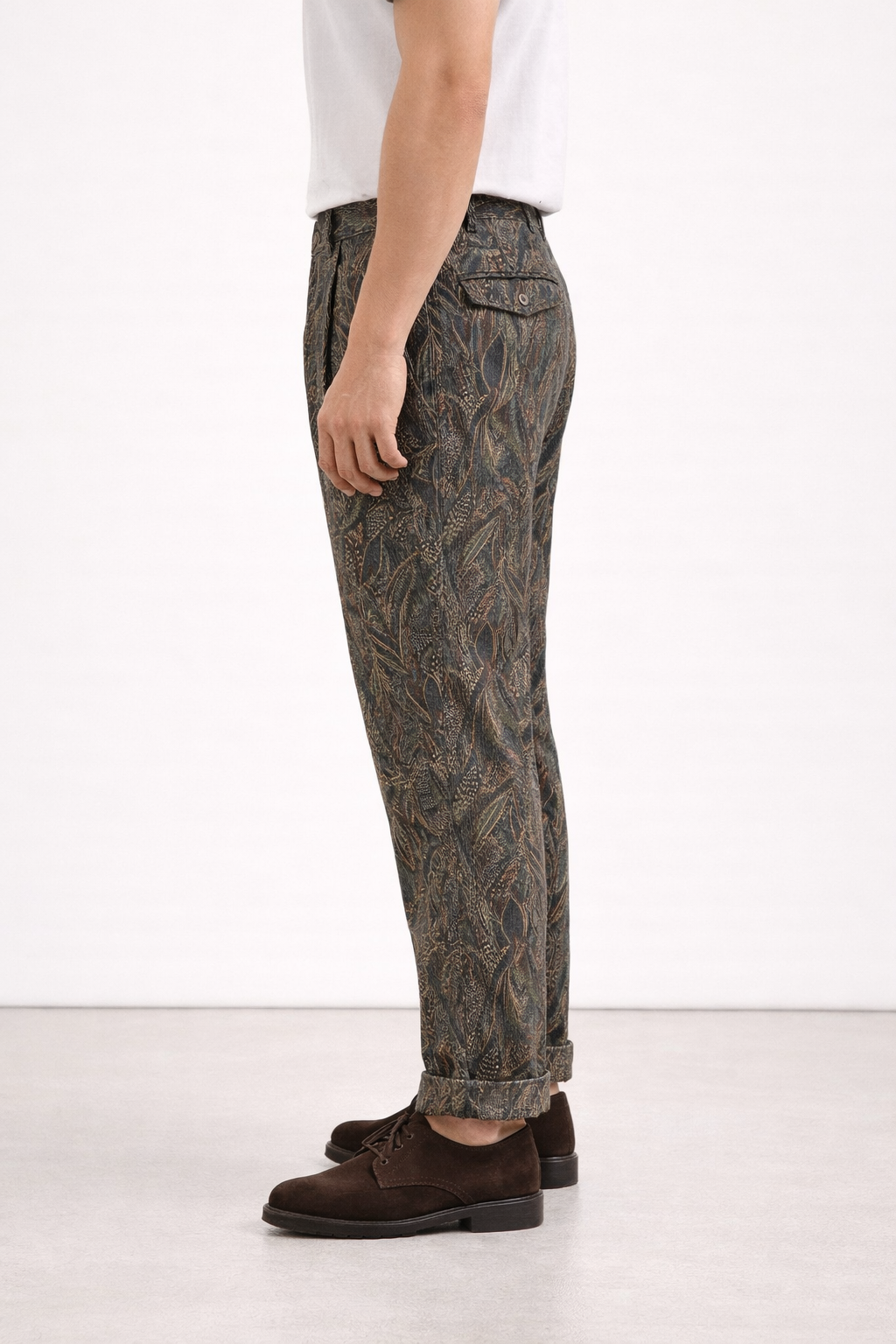 A model wearing Germano 1952 green corduroy trousers with forest themed pattern from behind.