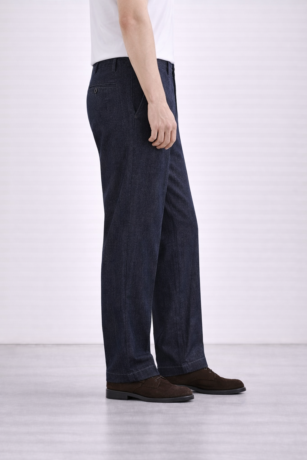 A side on image of a model wearing Germano 1952 denim trousers with a pleat.