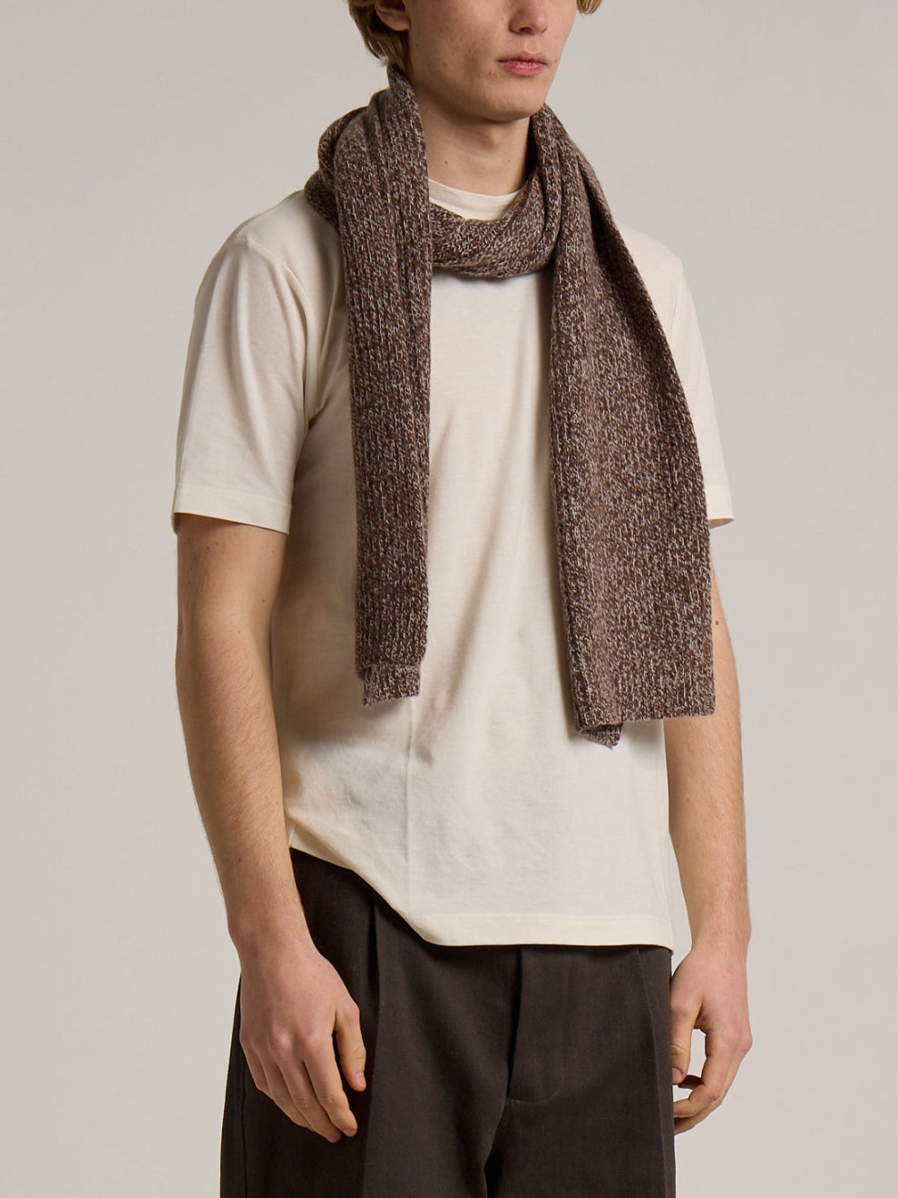 A model wearing a Wool&Co lambswool blend scarf in brown with white pattern.