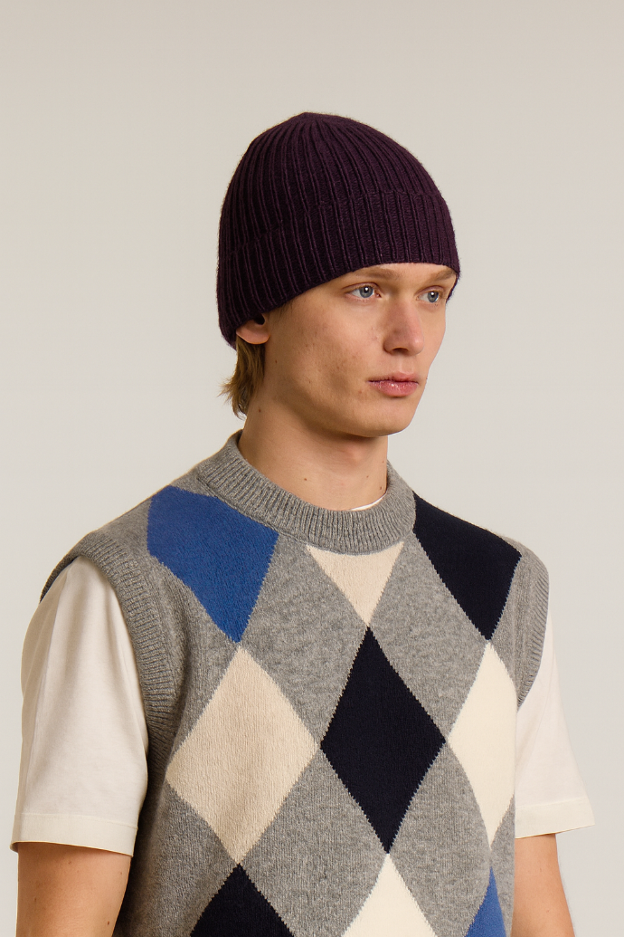 A model wearing a Wool&Co Merino wool blend beanie hat in burgundy.